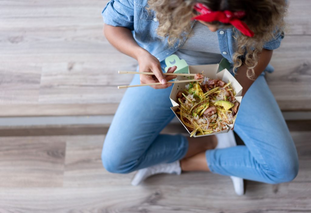 Gros plan sur une femme mangeant un poke bowl à la maison lors d'un déménagement.