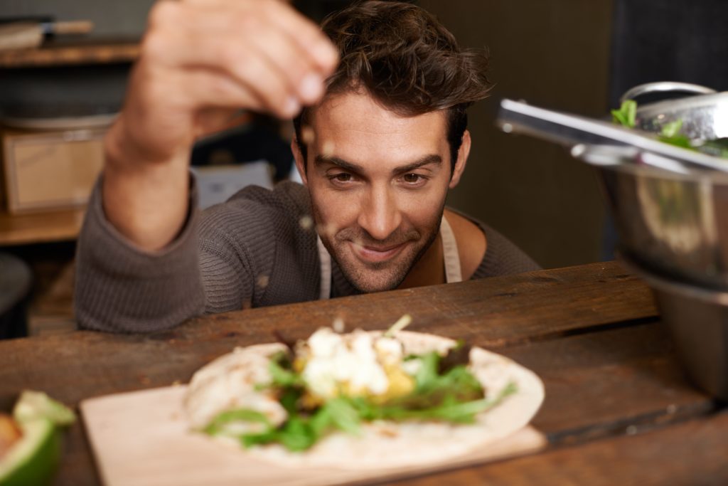 Photo d'un beau jeune homme préparant un repas dans son stand de nourriture.